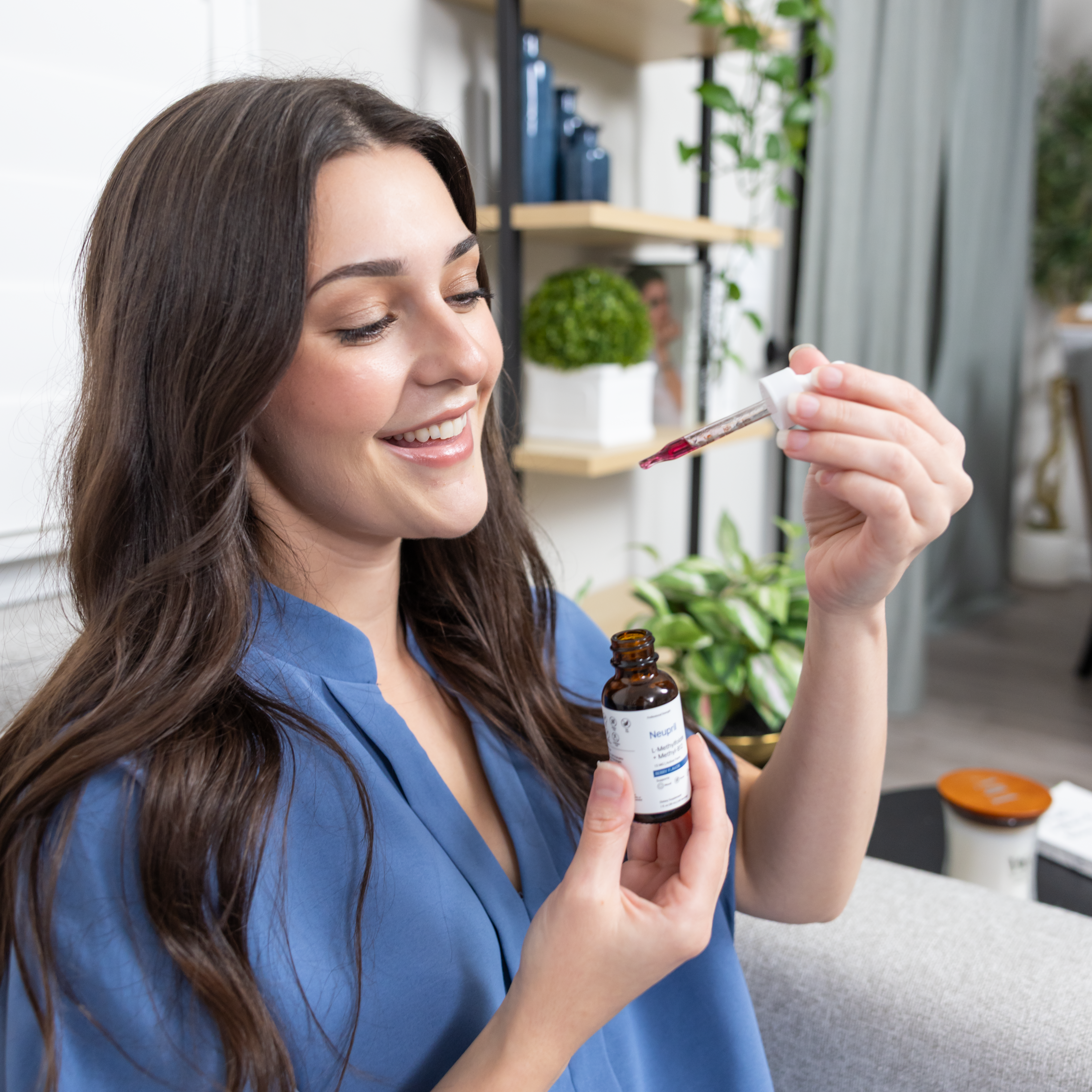 Woman holding a bottle of Neupril and a dropper in a home setting