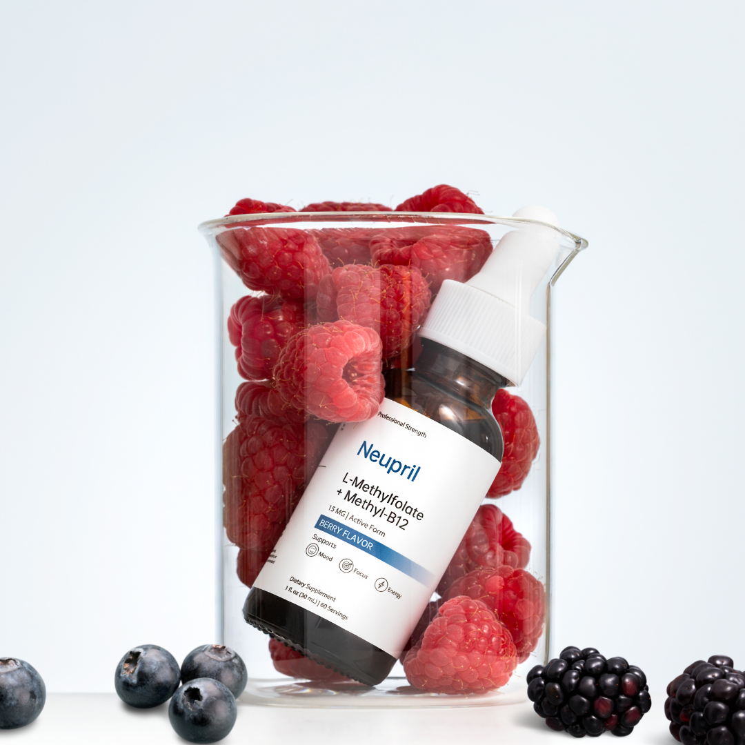 A glass science beaker filled with fresh red raspberries, with a bottle of Neupril Professional Strength L-Methylfolate + Methyl-B12 leaning inside it. Fresh blueberries and blackberries are scattered at the base against a clean white background.