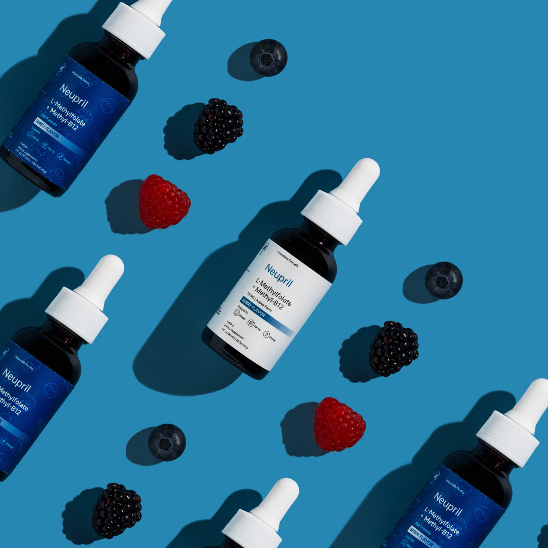 A dynamic diagonal flat-lay pattern featuring Neupril and Neupril Kids L-Methylfolate + Methyl-B12 bottles. The amber glass droppers are interspersed with fresh raspberries, blackberries, and blueberries on a solid blue background with sharp, modern shadows